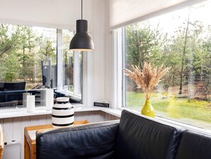 A modern living room with a black leather sofa, a yellow vase with dried plants, and a black pendant light. - 6 Person Holiday Home in Blokhus (Blokhus)