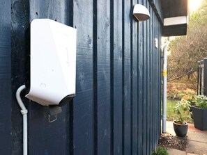 A white outdoor electrical box mounted on a dark blue wall, with a white pipe connected to it. - 6 Person Holiday Home in Blokhus (Blokhus)