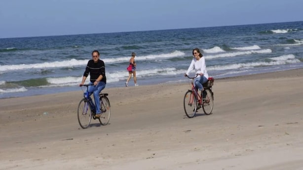 A beach with two cyclists and a pedestrian in the background. - 6 Person Holiday Home in Blokhus (Blokhus)
