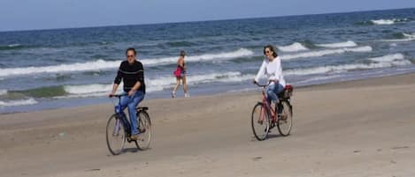 A beach with two cyclists and a pedestrian in the background.