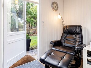 A room with a leather recliner chair, a wall clock, and a door leading to a garden. - 6 Person Holiday Home in Blokhus (Blokhus)