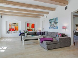 Un salón amplio con un sofá gris, una mesa de centro y un cuadro en la pared.