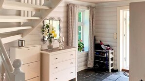 Gradi que condueixen a una habitació amb una petita taula blanca, un mirall i una finestra amb cortines.