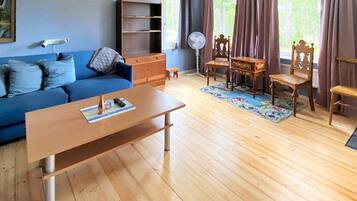 A living room with a blue sofa, wooden coffee table, and a fan.