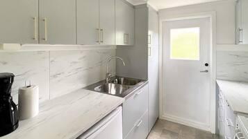 A kitchen with white cabinets, a sink, and a coffee maker.