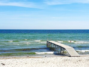 A wooden pier extending into the ocean with clear skies above.