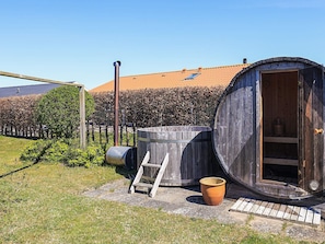 A rustic outdoor setting with a wooden barrel, a ladder, and a large wooden structure with an open door.