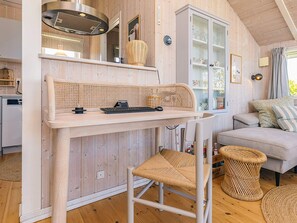 A cozy room with a wooden interior, a dining table with a woven chair, a sofa, and a cabinet with glass doors.