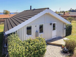 A small white building with a sloped roof, a front door, and windows. - Holiday Home in Jægerspris (Jægerspris)