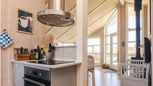 A kitchen with a built-in oven, a stove, a sink, and a large window. - Holiday Home in Jægerspris (Jægerspris)