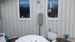 Ein eingeschossiges Gebäude mit zwei Fenstern, einer Tür und einem sichtbaren Stromkasten.