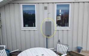 Ein eingeschossiges Gebäude mit zwei Fenstern, einer Tür und einem sichtbaren Stromkasten.