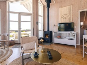 A cozy living room with a fireplace, a television, and a comfortable seating area. - Holiday Home in Jægerspris (Jægerspris)