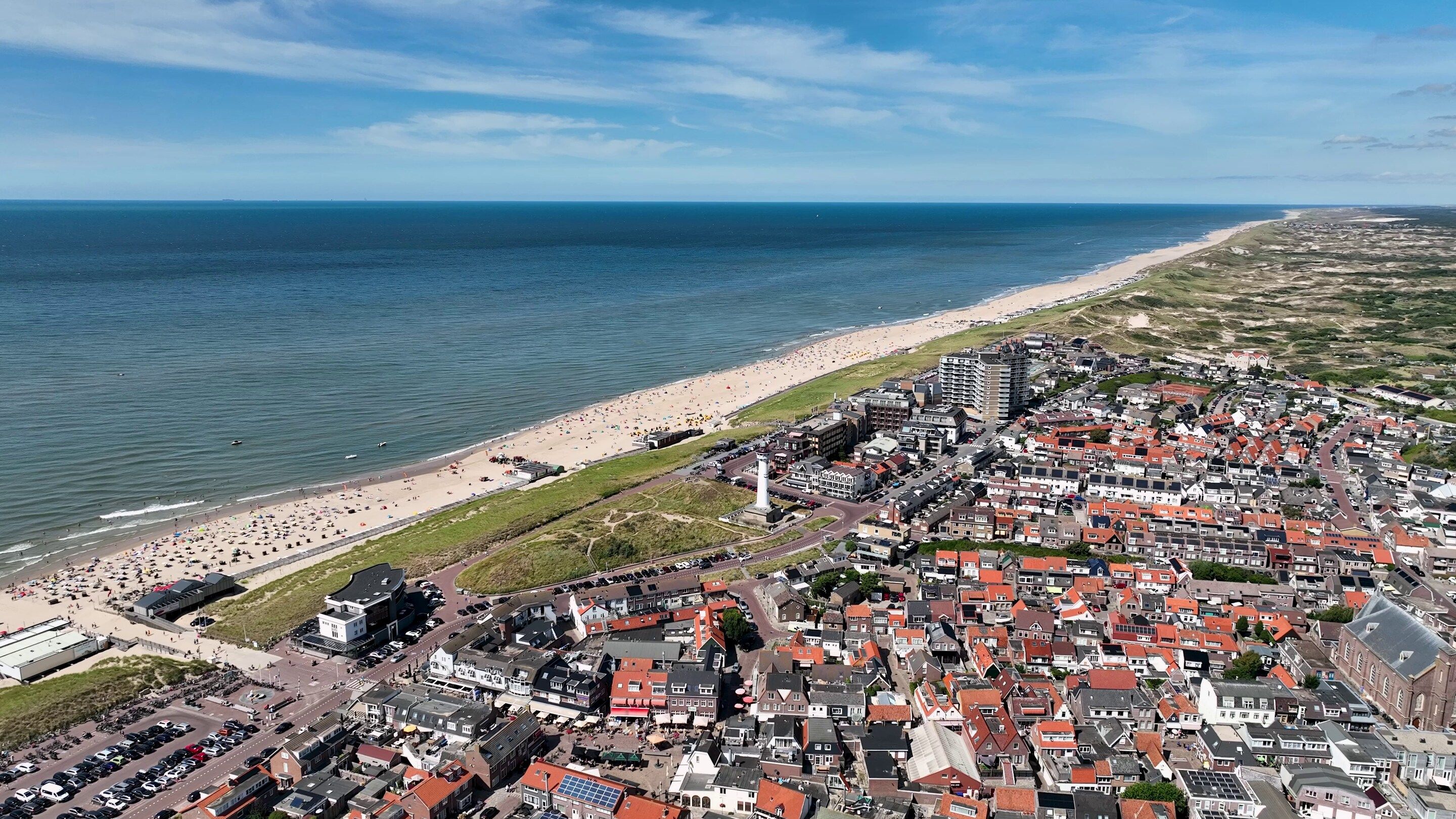 Une ville côtière avec une plage, des bâtiments et un phare.