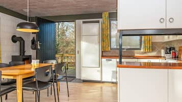 Una cocina moderna con armarios blancos, encimera de madera y horno empotrado.