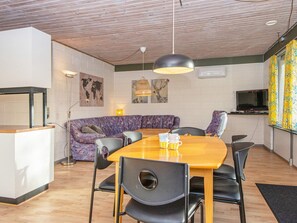 A modern living space with a wooden ceiling, a sofa, a dining table with chairs, and a television. - 6 Person Holiday Home in Ans By (Farvang)