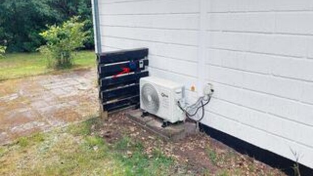 An outdoor air conditioning unit mounted on a wall, a power outlet, and a hose connected to the unit. - 6 Person Holiday Home in Ans By (Farvang)