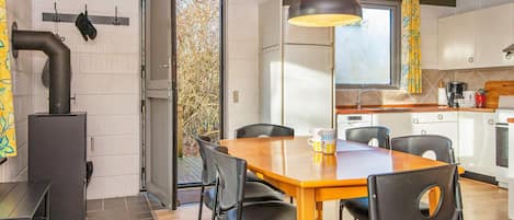 A modern kitchen with a dining area, a stove, and a large window.