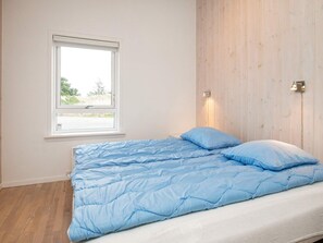 A bedroom with a bed, a window, and a wall-mounted light fixture.