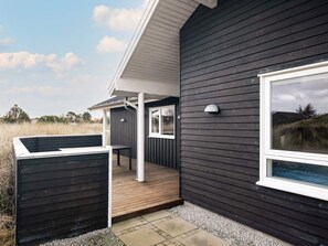 A modern building with a dark exterior, a covered outdoor seating area, and a large window. - Holiday Home in Ã…lbÃ¦k (Aalbaek)