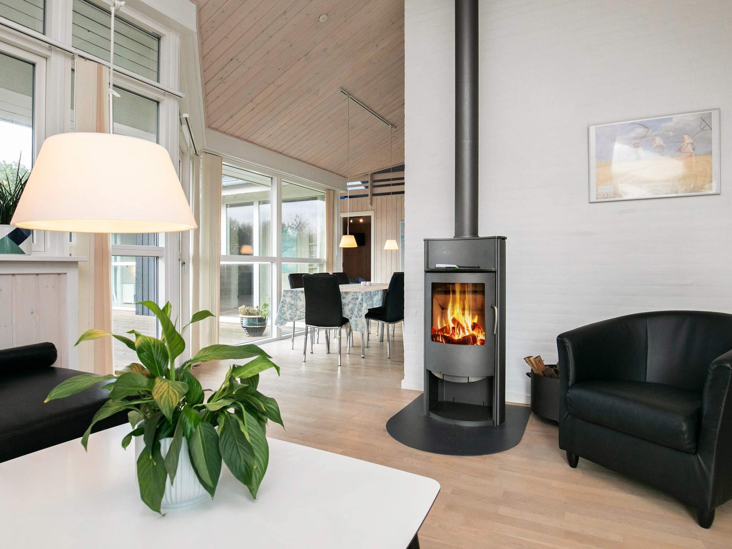 A modern living room with a fireplace, a dining area, and a large window.