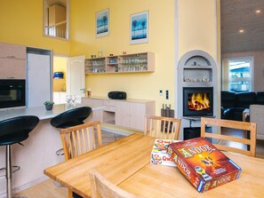 A modern kitchen with a dining area, a fireplace, and a bookshelf. - 4 Star Holiday Home in Tarm (Tarm)