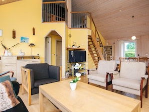 A spacious living area with a sofa, chairs, a coffee table, and a TV. A staircase leads to an upper level. - 4 Star Holiday Home in Tarm (Tarm)