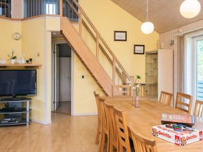 A dining area with a wooden table and chairs, a television, and a staircase leading to an upper level. - 4 Star Holiday Home in Tarm (Tarm)