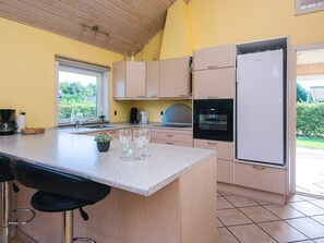 A kitchen with a central island, a refrigerator, and a window.