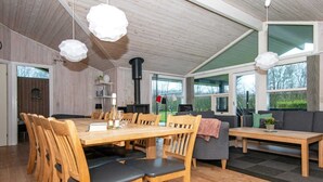 Tilava huone, jossa on puinen ruokapöytä ja -tuolit, sohva ja takka.