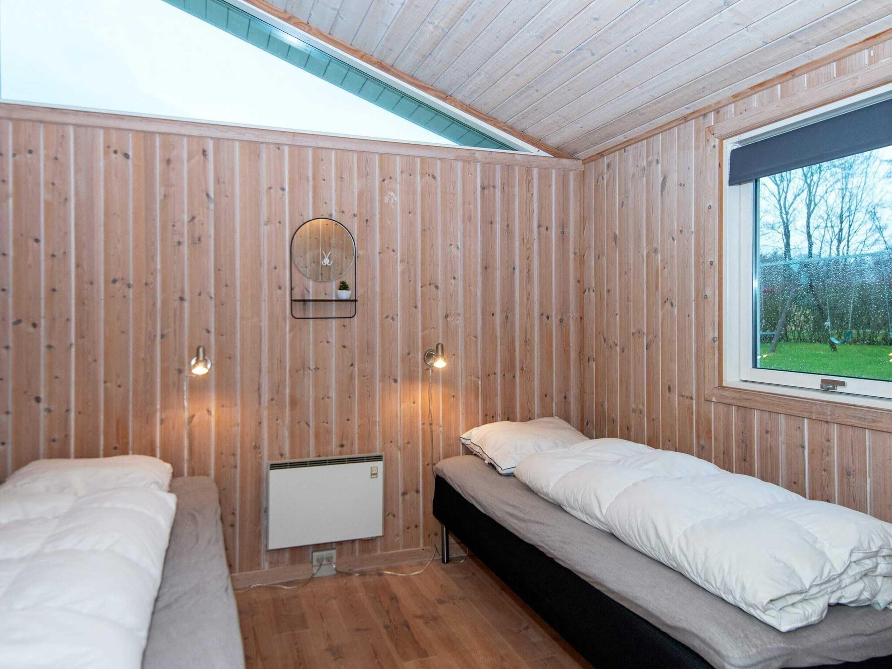 A cabin room with two beds, a wooden wall, a window with a view, and a small shelf with a mirror and a plant.