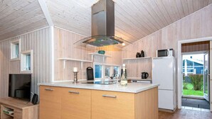 Moderni keittiö, jossa on puiset kaapit, keskeinen keittiösaareke ja sisäänrakennettu mikroaaltouuni.
