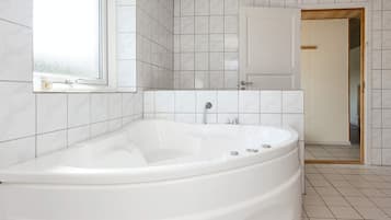 A modern bathroom with a freestanding bathtub, white tiled walls, and a wooden ceiling.