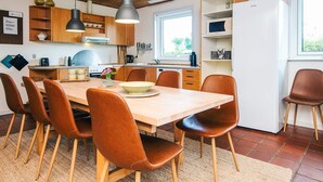 A modern kitchen with wooden cabinets, a central island, and a dining area with chairs. - Holiday Home in Odder (Odder)
