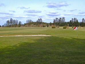 Un campo da golf con una buca di sabbia e un traliccio che segnala una buca.
