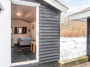 A small, single-room cabin with a bed, a chair, and a small table. - 6 Person Holiday Home in Toftlund (Toftlund)