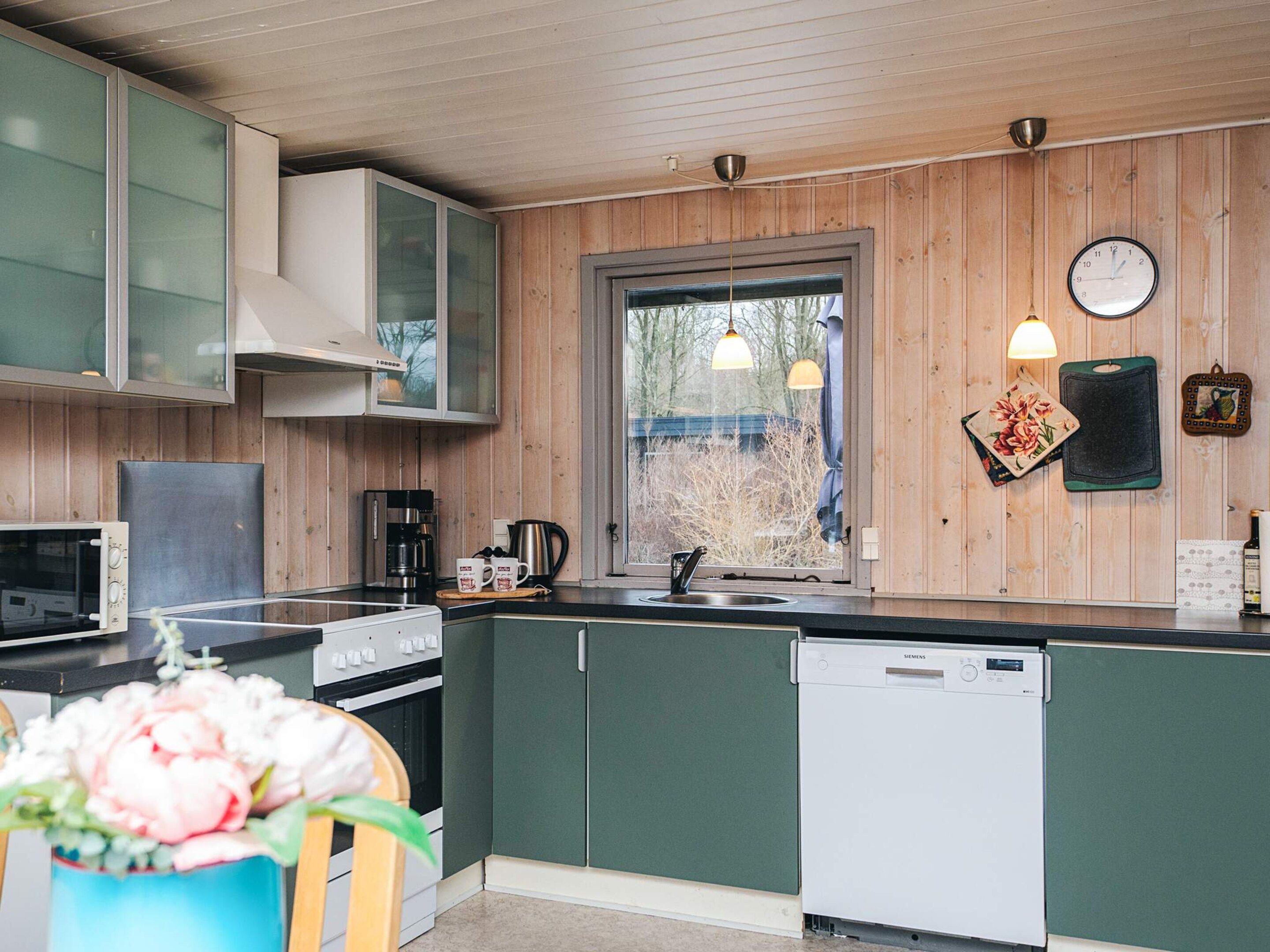 Una cocina moderna con armarios de madera, horno empotrado, cafetera y lavavajillas.