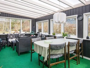 A dining area with a table and chairs, large windows, and a ceiling with skylights. - 8 Person Holiday Home in Logstor (Logstor)