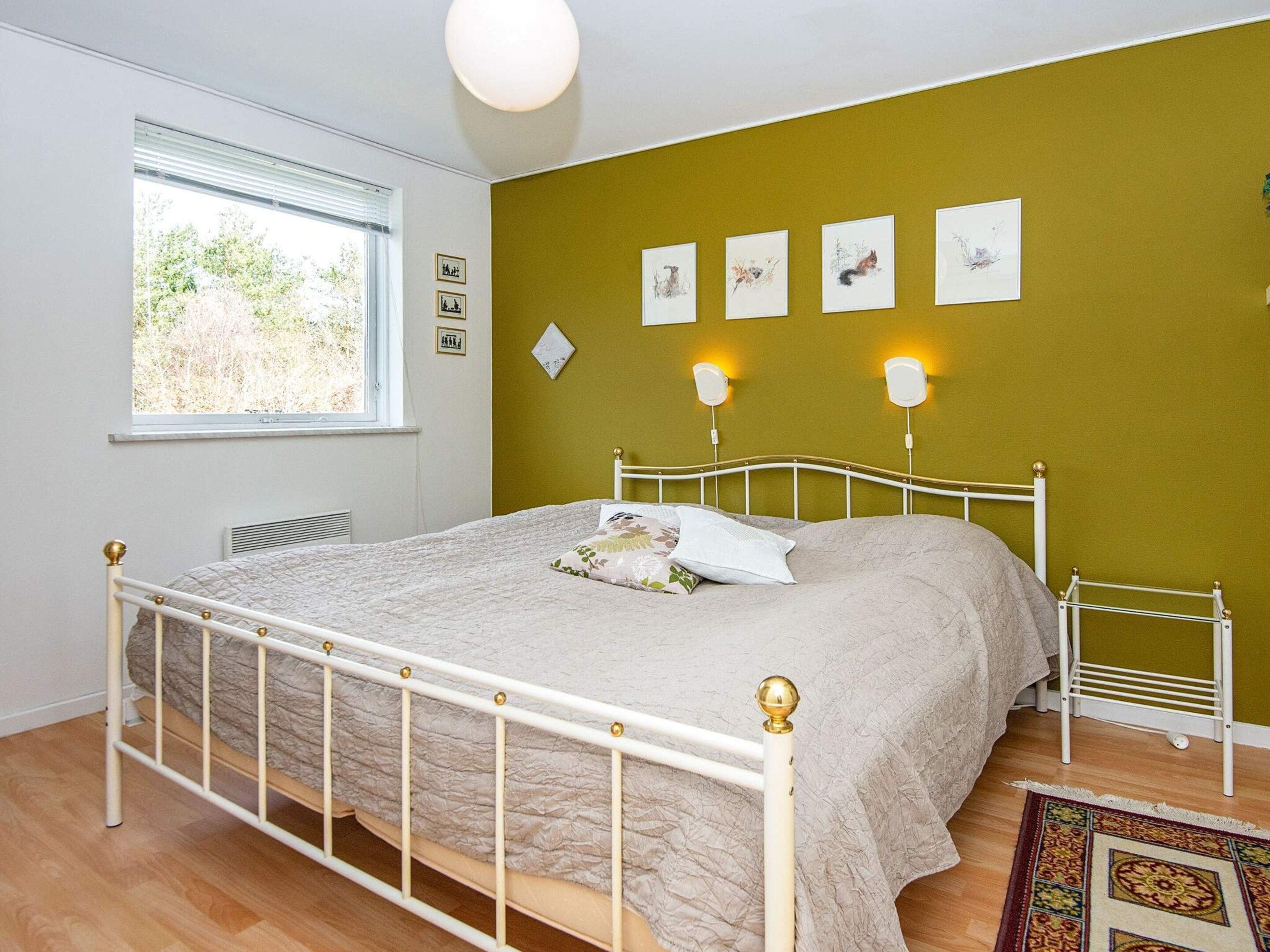 A bedroom with a bed, a window, and wall-mounted artwork.