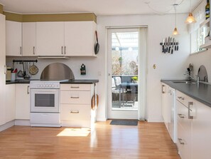 A modern kitchen with white cabinets, a stove, and a dining area with a table and chairs.