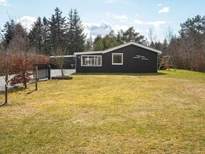 A single-story building with a dark exterior, a visible garage door, and a fenced yard. - 8 Person Holiday Home in Logstor (Logstor)