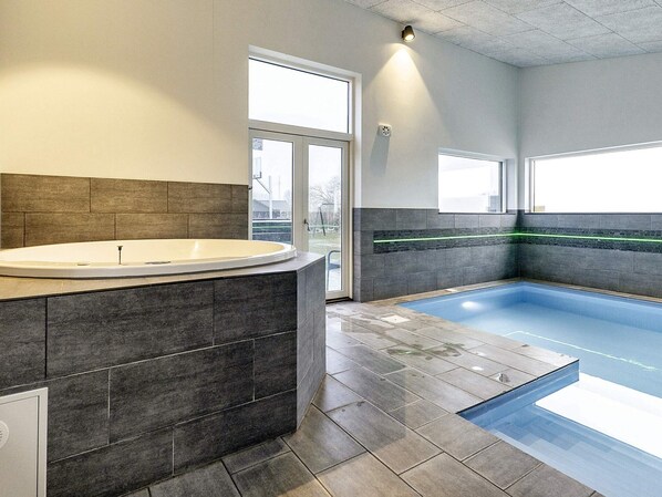 A modern bathroom with a freestanding bathtub, a glass-enclosed pool, and a large window providing natural light.
