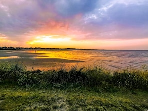 A coastal landscape with a sunset, grassy foreground, and a distant shoreline. - Holiday Home in Væggerløse (Vaeggerlose)