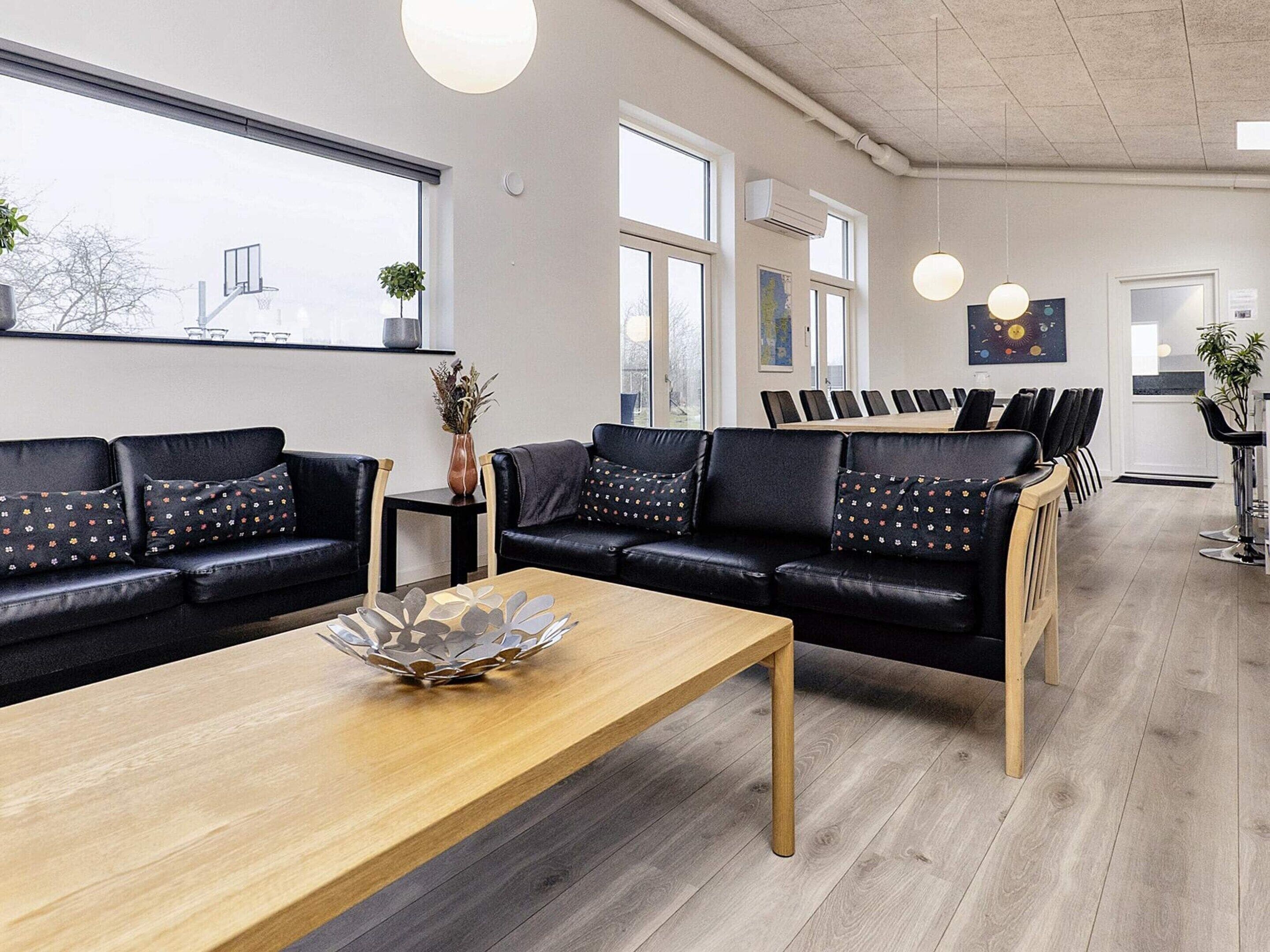 Ein modernes Interieur mit einer Sofagarnitur, einem Holztisch und einem Essbereich mit Stühlen.