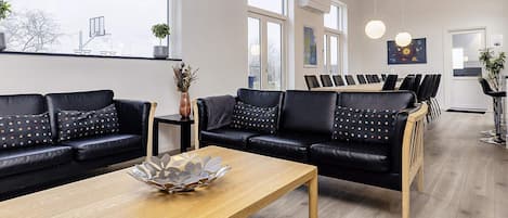 A modern interior with a sofa set, a wooden coffee table, and a dining area with chairs.