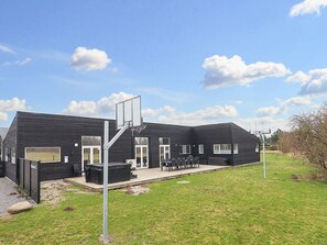 A building with a basketball hoop, outdoor seating, and a grassy area.