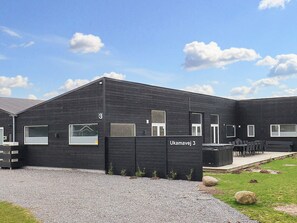 A building with a black exterior, a gravel driveway, and a sign reading 'Ukamavej 3'.