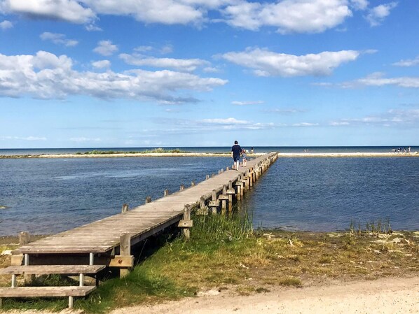 Un muelle de madera que se adentra en una masa de agua, con un cielo despejado.