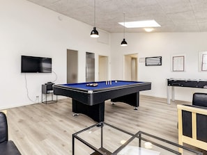 A pool table in a room with a flat-screen TV, a foosball table, and a glass coffee table. - Holiday Home in Væggerløse (Vaeggerlose)