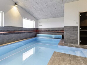 A swimming pool with a tiled floor and walls, a bench, and a window.